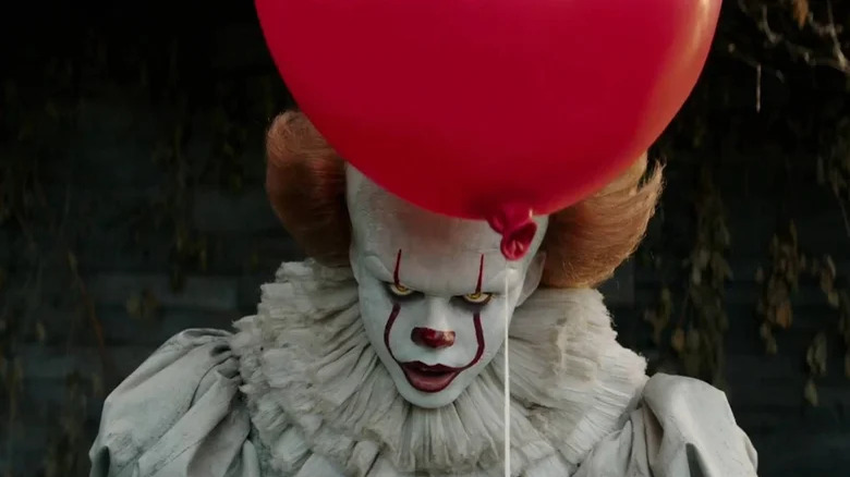 Pennywise se uită amenințător în timp ce ținea un balon în El