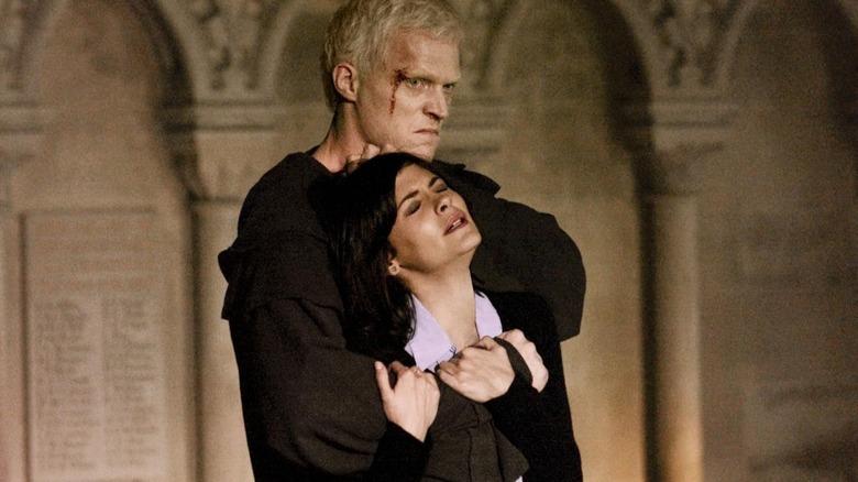 Călugărul albino Silas, sângerând de la o rană de pe frunte, ținând ostatic pe Nevau