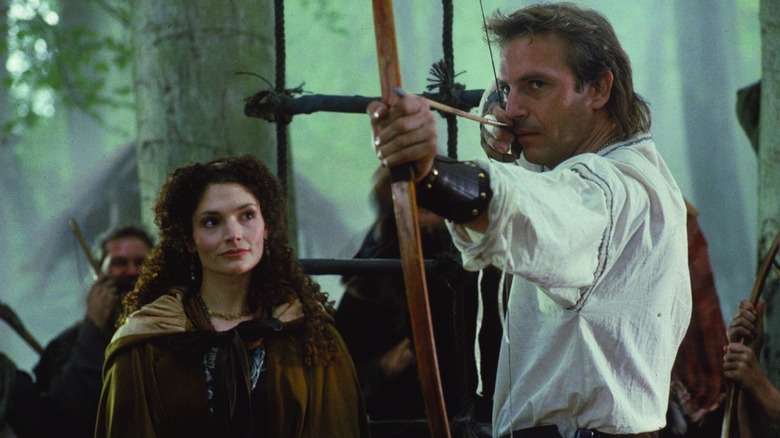 Mary Elizabeth Mastrantonio în rolul Lady Marian îl privește pe Kevin Costner în timp ce Robin trage o împușcătură în Robin Hood: Prince of Thieves