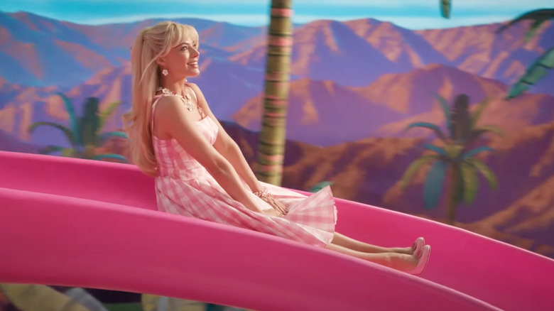 Margot Robbie coborând toboganul Dream House în Barbie
