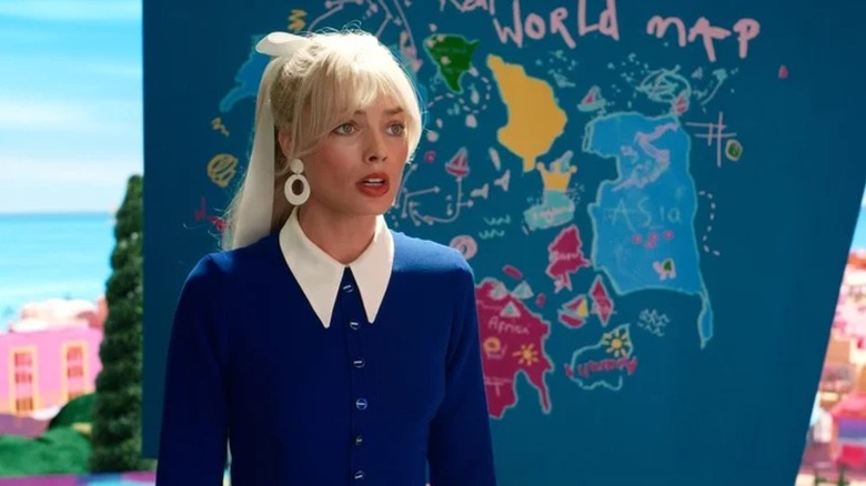 Margot Robbie stând în fața hărții lui Weird Barbie în Barbie
