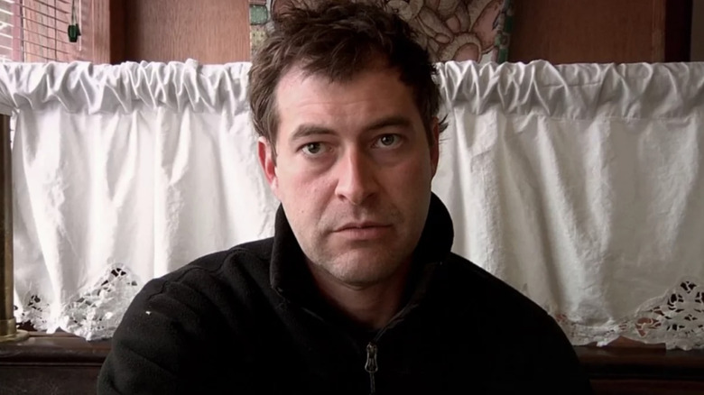 Mark Duplass arăta deznădăjduit, privind în jos camera în timp ce stă într-un restaurant din Creep