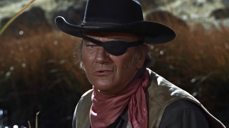 Cocoșul Cogburn stând pe lângă râu în True Grit