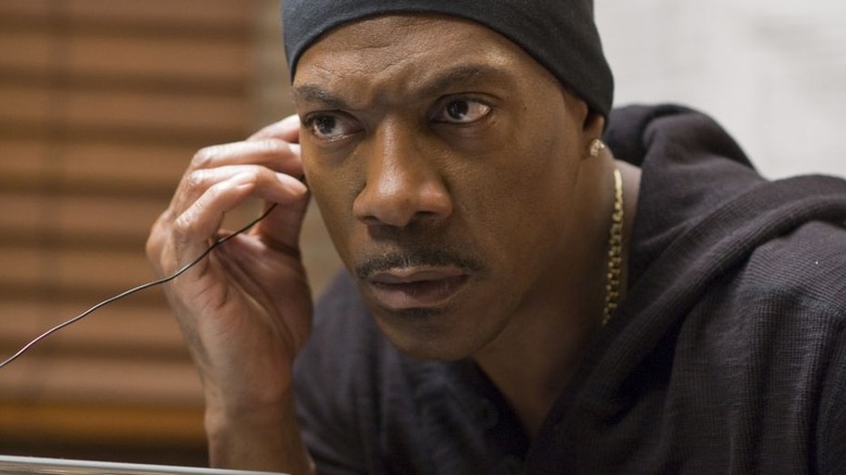 Glisează pe Davis ținându-și un fir la ureche, încercând să spargă un seif.