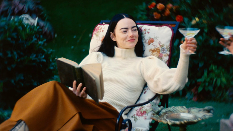 Bella pe un șezlong ținând o băutură în Poor Things