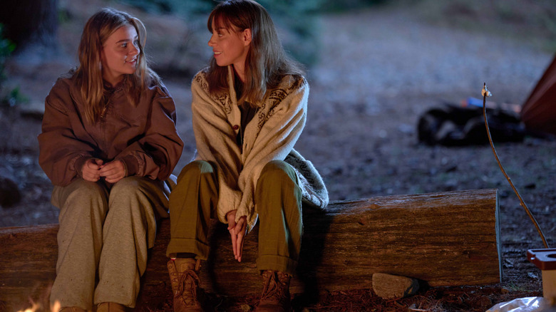 Maisy Stella în rolul lui Elliott și Aubrey Plaza în rolul ei mai în vârstă care stă lângă un foc de tabără în My Old Ass