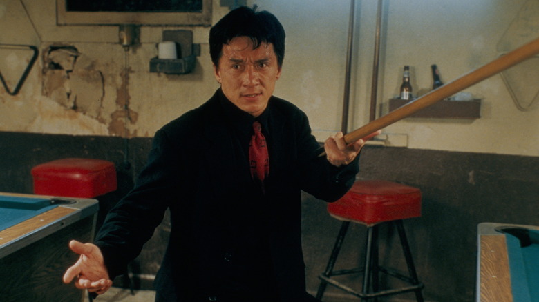 Jackie Chan în rolul inspectorului șef Lee ținând un tac de biliard ca o armă în ora de vârf