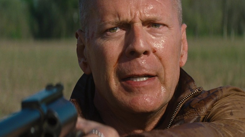 Bruce Willis în rolul lui Old Joe care arată transpirat și ține o armă în Looper