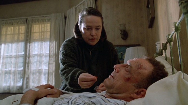 Annie Wilkes îi dă lui Paul Sheldon o pastilă în timp ce este țintuit la pat în Misery