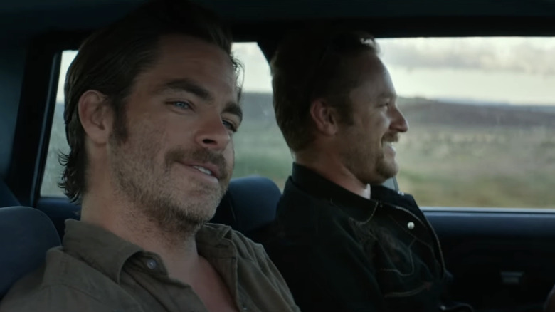 Toby Howard din Chris Pine zâmbește în timp ce stă alături de Tanner Howard al lui Ben Foster pe scaunul pasagerului unei mașini în Hell or High Water