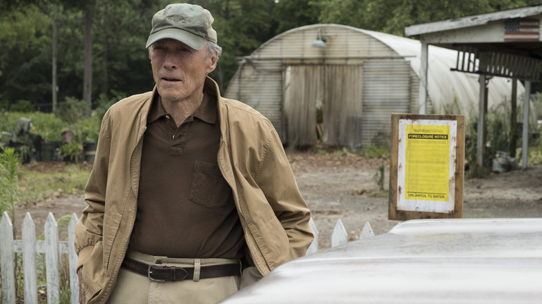 Clint Eastwood ca Earl Stone purtând o șapcă de baseball și stând deoparte un camion în The Mule