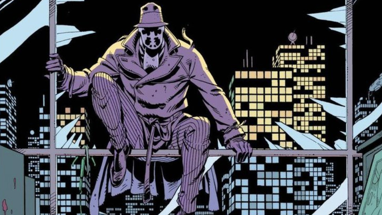 Rorschach așezat pe tocul ferestrei sparte în Watchmen