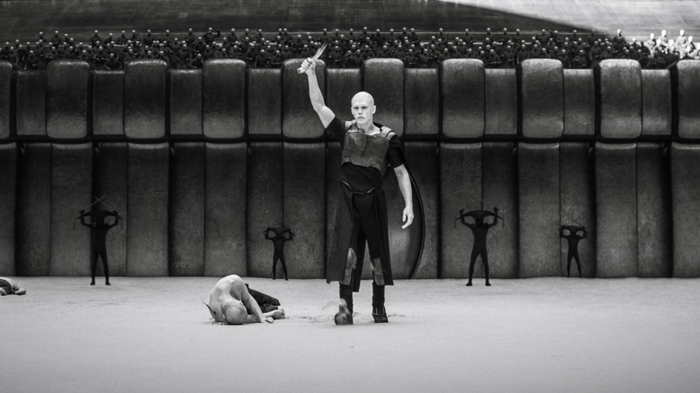 Feyd-Rautha Harkonnen ridicându-și lama triumfător în centrul arenei pe Giedi Prime în Dune: Part Two