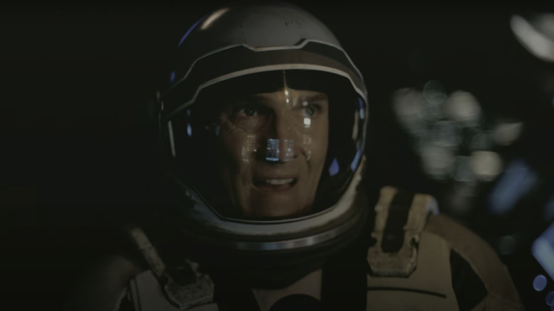 Joseph al lui Matthew McConaughey "Coop" Cooper ridică privirea în timp ce stă într-o navetă spațială din Interstellar