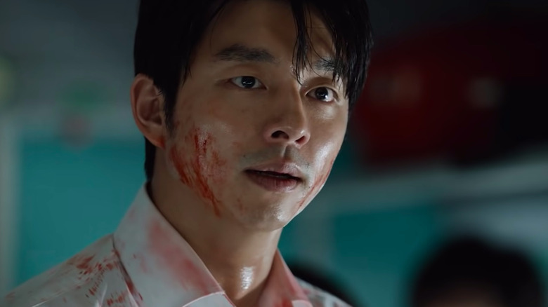 Gong Yoo în rolul lui Seok Woo cu sânge pe față și o expresie îngrijorată în Train to Busan