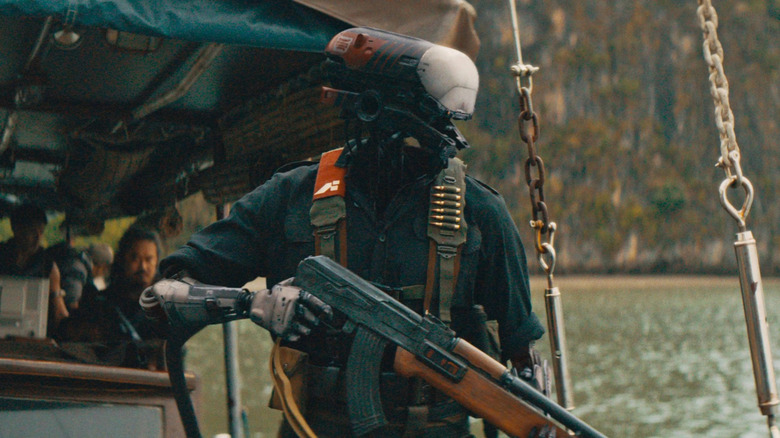 Un polițist robot care debarcă de pe o navă militară. Are o armă în mână în The Creator