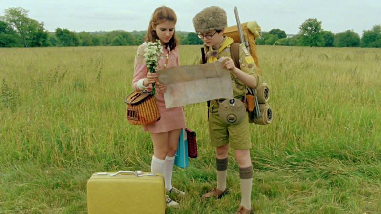 Suzy a lui Kara Hayward și Sam al lui Jared Gilman citind harta într-un câmp din Moonrise Kingdom