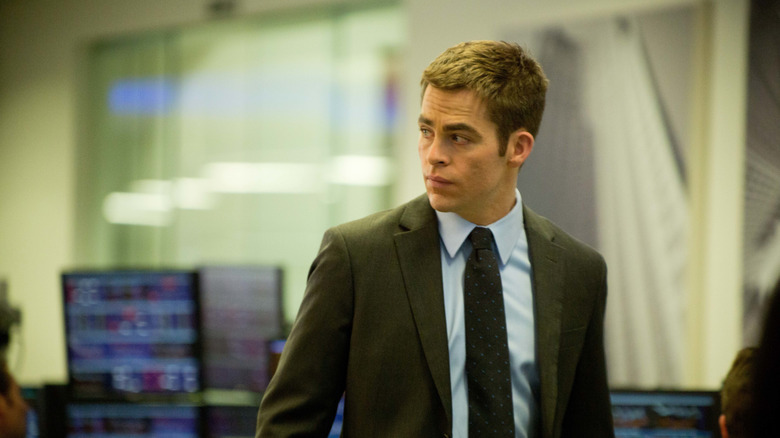 Jack Ryan într -un costum privind peste umăr cu calculatoare pe fundal în Jack Ryan: Shadow Recrut