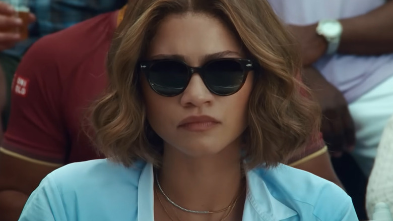 Tashi poartă ochelari de soare și se uită la meciul lui Art și Patrick în Challengers