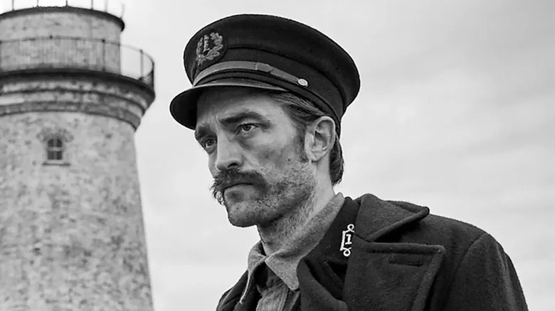Ephraim Winslow/Thomas Howard al lui Robert Pattinson se află în afara farului, privind la distanță în distanță în far