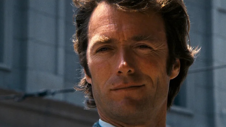 Harry Callahan de la Clint Eastwood se uită la distanță pe un fundal al clădirilor din Dirty Harry