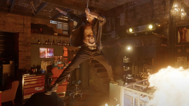 Tatuajul artist fiind ținut de un lanț și ținut deasupra focului în destinația finală: Bloodlines