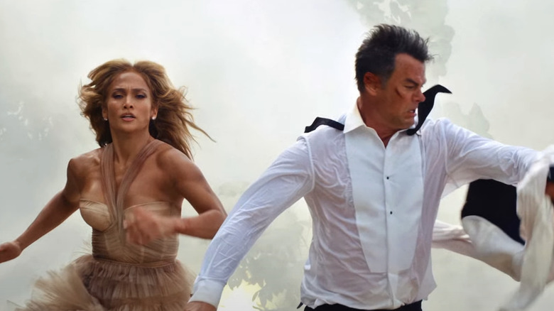 Darcy Rivera al lui Jennifer Lopez și Tom Fowler al lui Josh Duhamel aleargă cot la cot pe o plajă în ținuta de nuntă în nunta cu pușcă