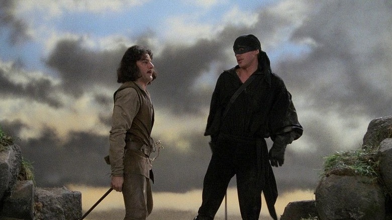 Inigo și omul în negru care stă lângă o stâncă.