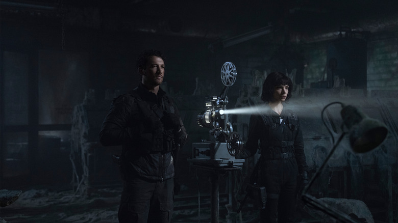 Anya Taylor-Joy ca Drasa și Miles Teller în timp ce Levi urmărind ceva de la un proiector în defileu