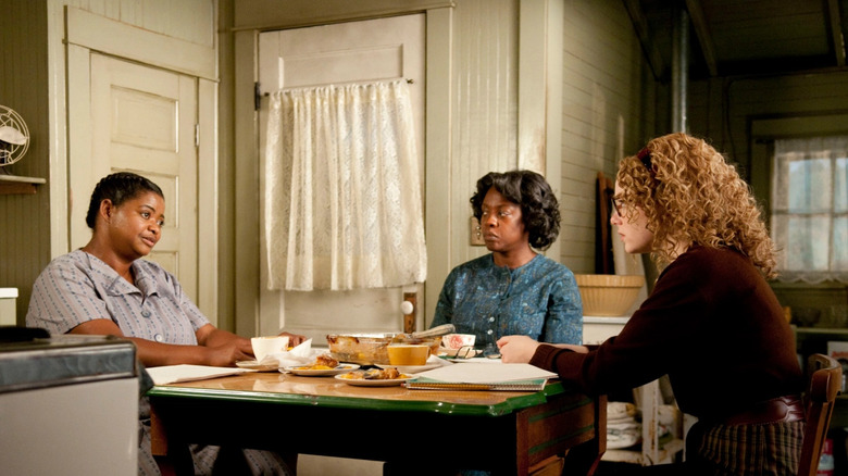Minny Aibilieen și Skeeter vorbind la o masă de bucătărie în ajutor