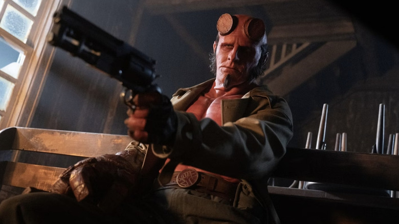 Hellboy arătând arma și stând în biserică în Hellboy: Omul strâmb