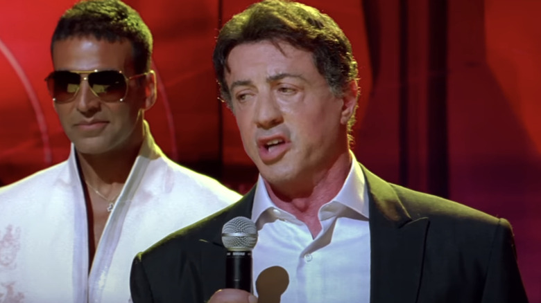 Viraj Shergill al lui Akshay Kumar stă în spatele lui Sylvester Stallone, în timp ce se adresează unei ceremonii de premiere în Kambakkht Ishq