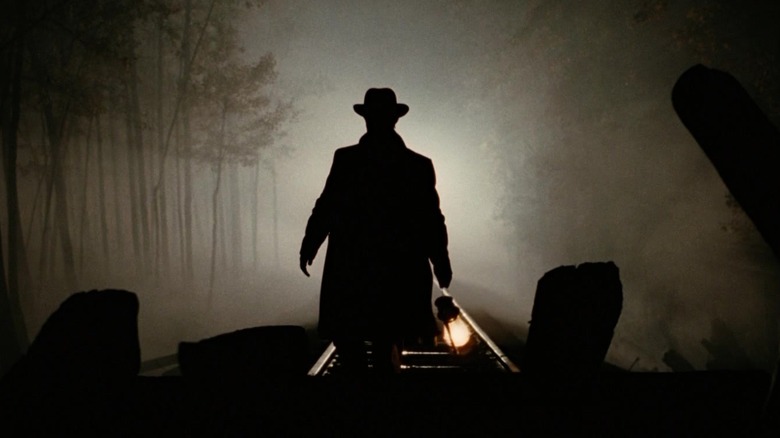 Jesse James de la Brad Pitt stă deasupra unui tren siluetat în asasinarea lui Jesse James de lașul Robert Ford