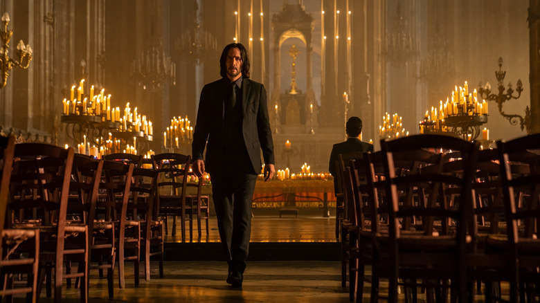 Keanu Reeves ca John Wick mergând spre spatele unei biserici, în timp ce Caine lui Donnie Yen este așezată în spatele lui în John Wick: Capitolul 4