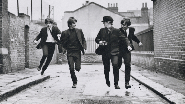 Paul McCartney, George Harrison, Ringo Starr și John Lennon sărind pe stradă într -o noapte grea