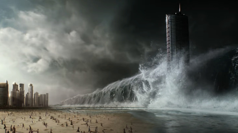 Un val de maree uriaș se ridică peste un oraș în timp ce oamenii de pe o plajă fug în Geostorm