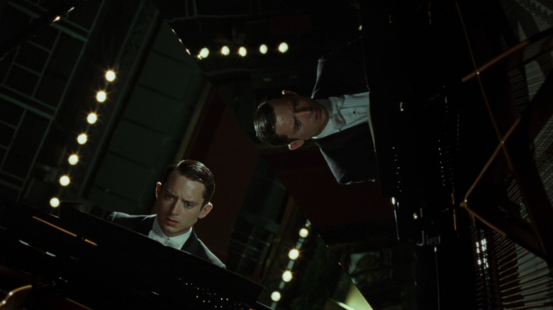 Elijah Wood în rolul lui Tom Selznick stând la pianul său (așa cum se arată din mai multe unghiuri) la pianul mare