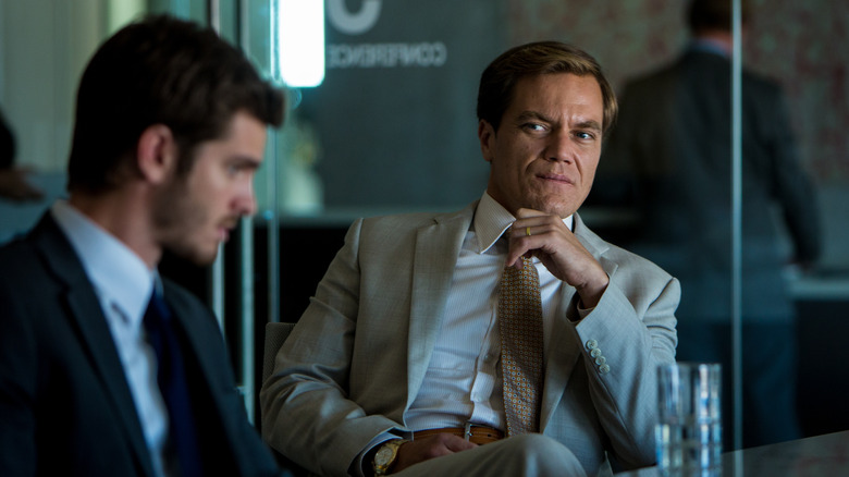 Michael Shannon, în timp ce Rick, privindu -l cu severă la Dennis de Andrew Garfield la masa de conferințe din 99 de case