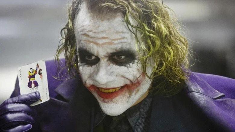 Jokerul lui Heath Ledger ținând o carte de joc în The Dark Knight