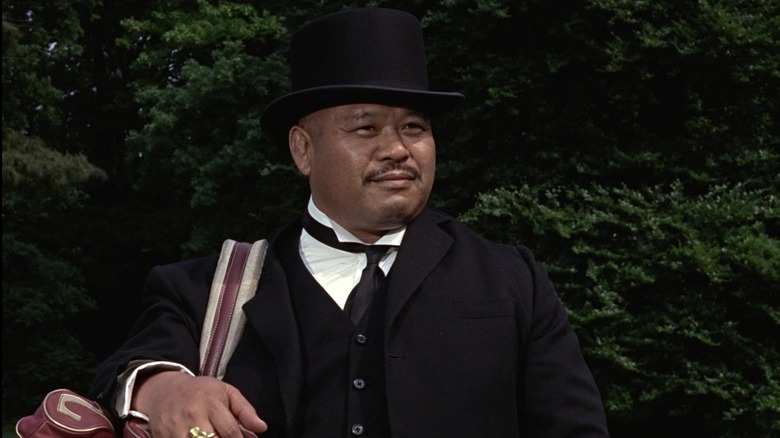 Odjob -ul lui Harold Sakata ține o pungă peste umăr în Goldfinger