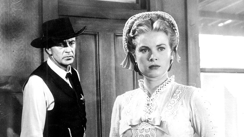 Gary Cooper în calitate de mareșal Will Kane, purtând o pălărie de cowboy neagră, se uită în spatele lui Grace Kelly în rolul lui Amy Fowler Kane, care se uită la stânga și este îngrijorat