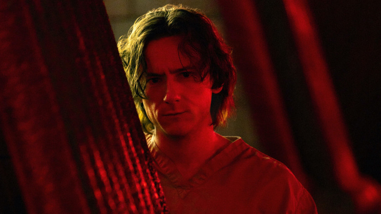 Bob Reynolds stând parțial ascuns în iluminat roșu în tunete