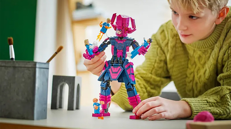 Un băiat se joacă cu setul Galactus vs Fantastic Four LEGO