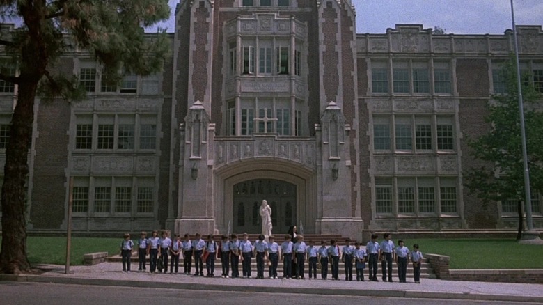 O linie de copii așteaptă în afara unei școli în petrecerea burlacilor