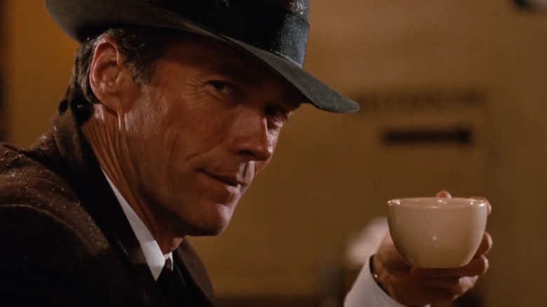 Strecură ținând o ceașcă de cafea în căldura orașului