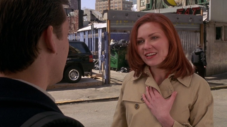 Mary Jane Watson (Kirsten Dunst) se află pe o stradă a orașului, ținând haina de tranșee bej închisă în Spider-Man