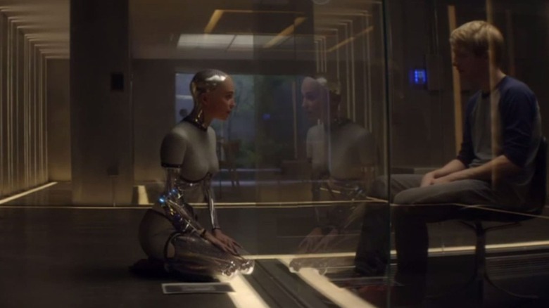 Ava Android (Alicia Vikander) și Caleb umanul (Domhnall Gleeson) vorbesc despre viața lor cu un perete de sticlă care le separă în ex Machina