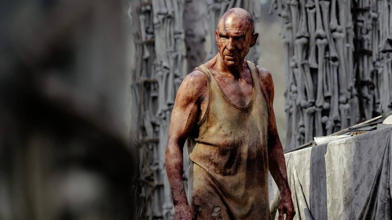 Ralph Fiennes în calitate de Dr. Kelson Bloody stând printre pilonii osoși în 28 de ani mai târziu