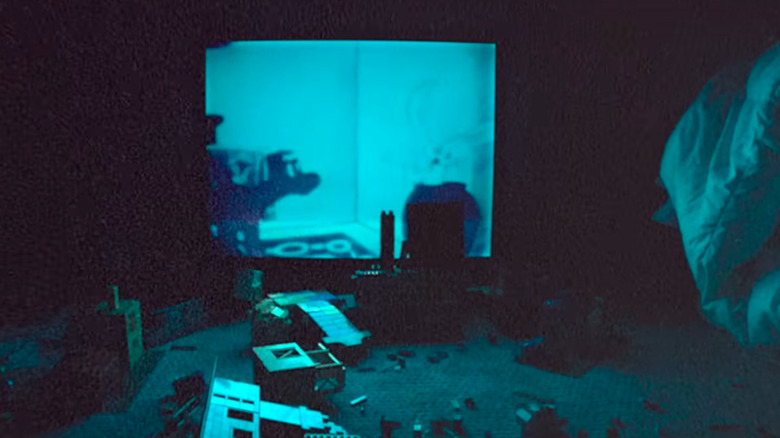 Jucării pe podea în fața unui televizor strălucitor în Skinamarink