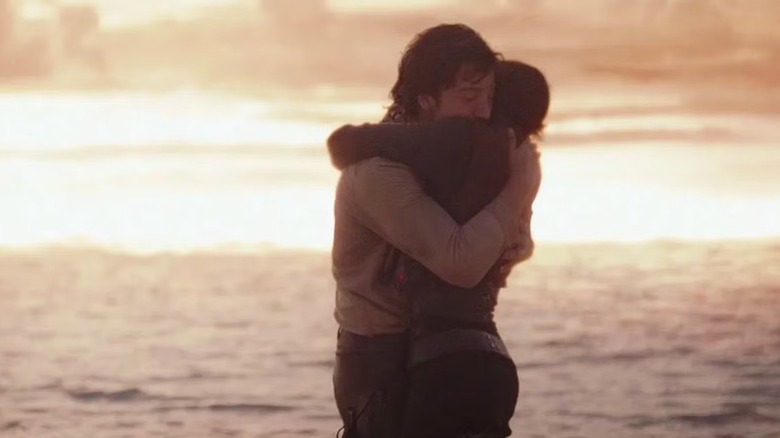 Jyn Erso și Cassian Andor ținându -se reciproc în timp ce vedeta morții îl aruncă pe Scarif în Rogue One